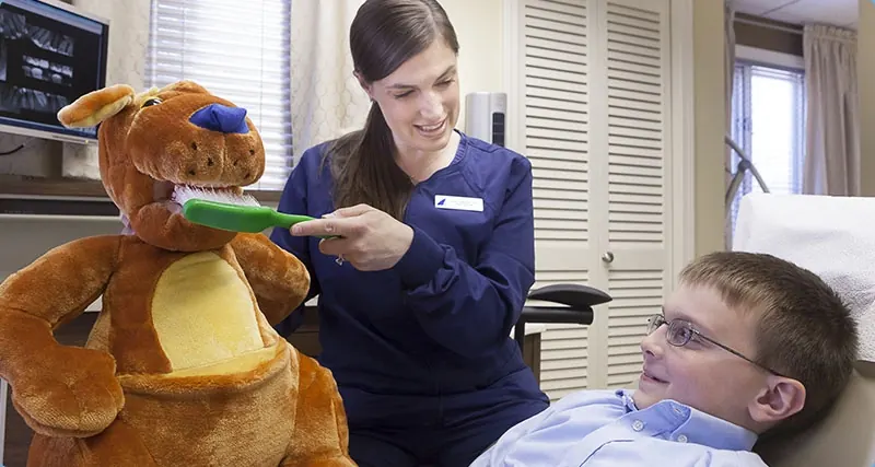 A hygienist at Hingham Dental Associates showing a young patient how to brush, using a puppet.