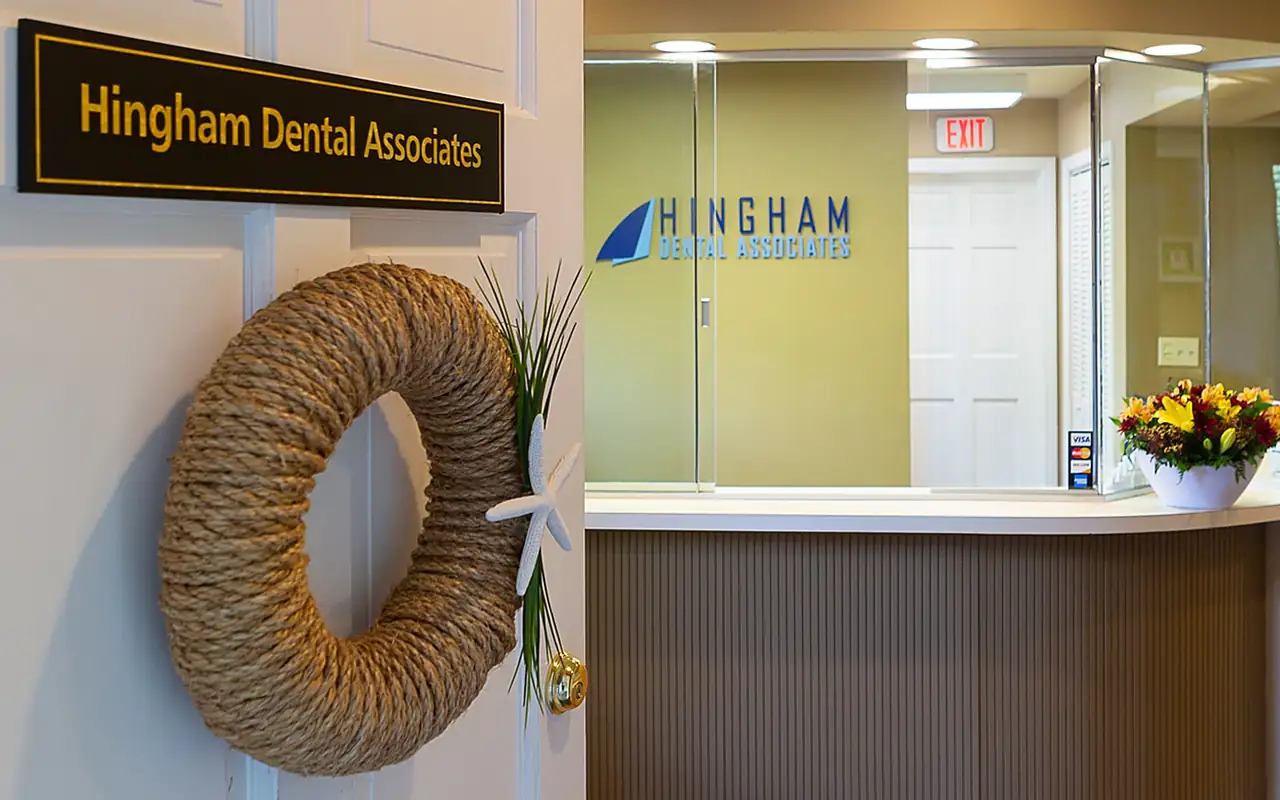 The reception at Hingham Dental Associates, with the practice's name plaque, a rope wreath and the front desk.